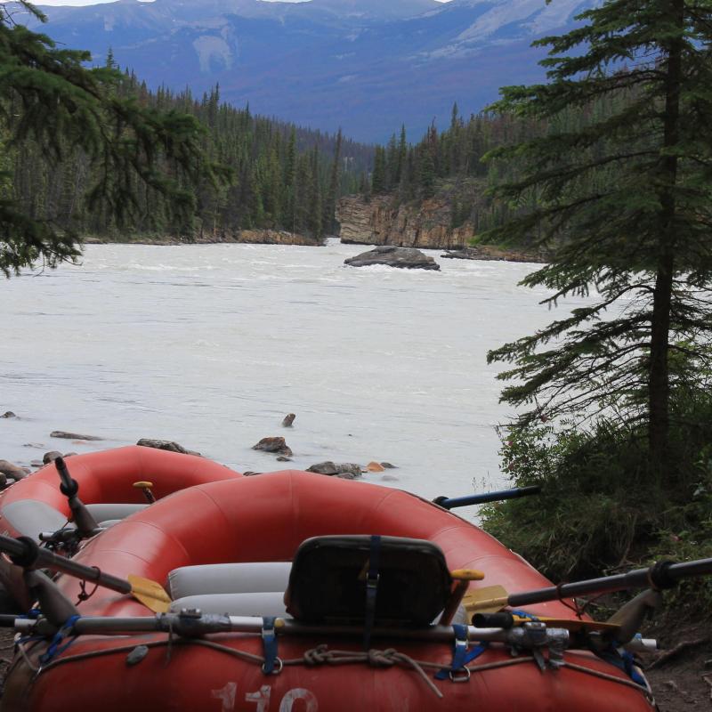 a red motorcycle parked on the side of a lake