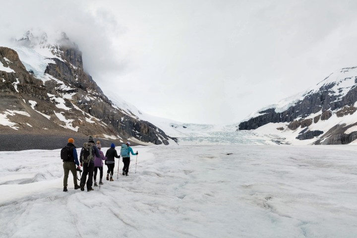 a group of people walking across a snow covered mountain